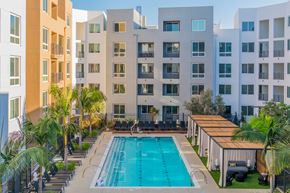 Costa Mesa apartment for rent - A swimming pool surrounded by lounge chairs and palm trees in front of apartment buildings. at Baker Block, Costa Mesa, CA