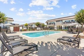 West Covina apartment for rent - A pool with sun loungers and a building in the background.
