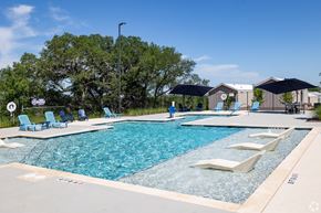 San Marcos apartment for rent - A large outdoor swimming pool with lounge chairs and umbrellas.