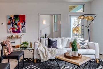Oklahoma City apartment for rent - A living room with a white couch, a black chair, a coffee table, and a colorful painting on the wall.