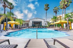 Upland apartment for rent - a swimming pool with yellow umbrellas and a white building in the background