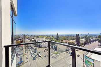 A view from a balcony overlooking a busy street with cars and buildings.