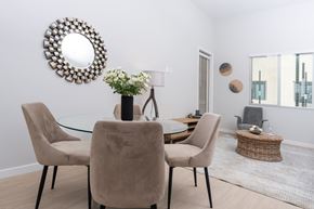 Ontario apartment for rent - Two Bedroom Luxury Apartments in Ontario, CA - Downtown Ontario Luxury Apartments - Dining Area with Round Dining Table, Tan Chairs, Decorative Wall-Mounted Mirror, and Wood Grain Vinyl Flooring.