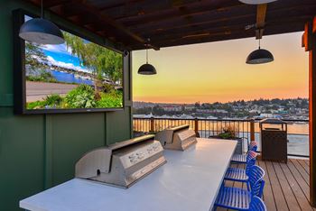 A balcony with a table, chairs and a television displaying a scenic view.
