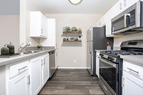Rancho Cucamonga apartment for rent - A kitchen with white cabinets and black appliances. at 55+ FountainGlen Terra Vista, California, 91730