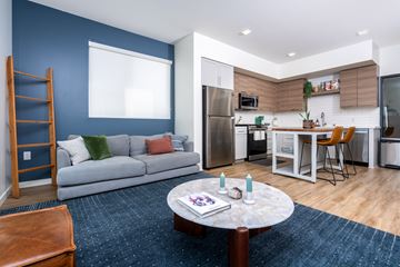 Sacramento apartment for rent - A modern kitchen with a dining table and chairs is adjacent to a living room with a sofa and a coffee table.