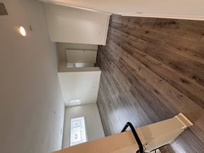 Corona townhouse for rent - A staircase with a wooden wall on the side and a white railing.