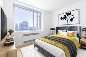Oakland apartment for rent - A modern bedroom with a large bed and a city view through the window.