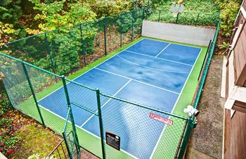 A tennis court surrounded by a green fence.