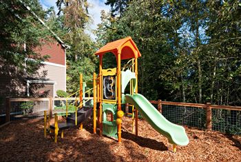 A playground with a green slide and a yellow and orange play structure.