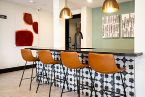 Los Alamitos apartment for rent - a kitchen with a large island with orange chairs and a painting on the wall