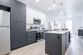 Oklahoma City apartment for rent - A modern kitchen with dark grey cabinets and a white countertop.