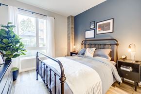Oakland apartment for rent - Downtown Oakland, CA Luxury Apartments Near Lake Merritt - Edson House - Bedroom With Floor Plant, Luxury Wood Finish Plank Flooring, Large Window, Concrete Pillar, Two Nightstands, and a Bed.