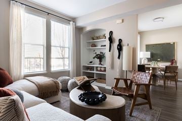 Napa apartment for rent - A living room with a white couch, a wooden chair, and a round table with a black object on it.