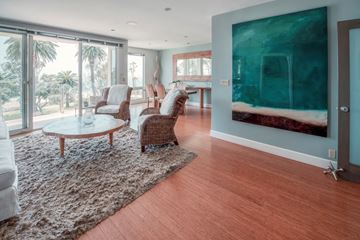 Santa Monica apartment for rent - A living room with a large painting on the wall and a glass door leading to a balcony.