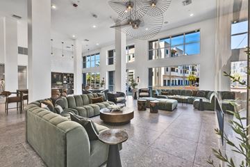 Oceanside apartment for rent - A large, modern living room with a long green couch and a circular table in the center.