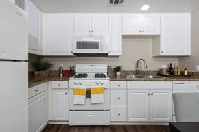 Riverside apartment for rent - A white kitchen with a stove top oven and a microwave above it.