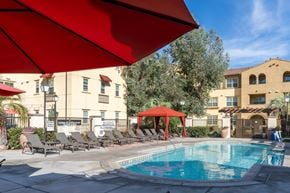 Riverside apartment for rent - A pool area with a red umbrella and lounge chairs.