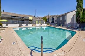 El Paso apartment for rent - A swimming pool surrounded by chairs and trees.