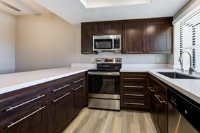 Laguna Niguel apartment for rent - Apartments for Rent Laguna Niguel CA - Pointe Niguel - Kitchen with Wood-Style Floor, Brown Cabinets, White Quartz Countertops, and Stainless Steel Appliances at Pointe Niguel, Laguna Niguel, CA