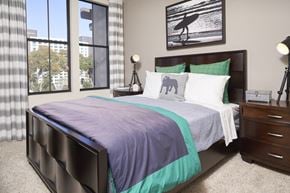 San Diego apartment for rent - Pet Friendly Apartments in Mission Valley CA - The Promenade Rio Vista - Bedroom Carpeted Floor, Bed, Nightstands with Lamps, Framed Wall Art, and Windows with Curtains at The Promenade Rio Vista, San