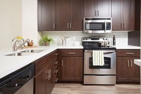 San Diego apartment for rent - Apartments in Mission Valley CA - The Promenade Rio Vista - Kitchen with Wood-Style Flooring, Dark Brown Cabinets, Ceramic Tile Countertops, Subway Tile Backsplash, and Stainless Steel Appliances