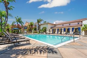Upland apartment for rent - A pool surrounded by lounge chairs and palm trees.