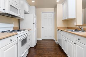 Upland apartment for rent - a kitchen with white cabinets and white appliances
