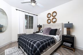 Irvine apartment for rent - A bedroom with a bed, a mirror, a dresser, and a ceiling fan.