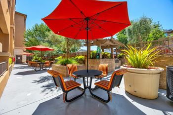 A patio with a table and chairs under a red umbrella