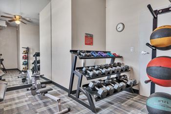 A gym with weights and dumbbells in the corner of a room