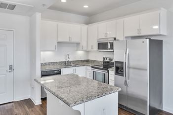 A kitchen with white cabinets and stainless steel appliances and granite counter tops