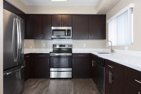 Palo Alto apartment for rent - 3 Bedroom Apartments in Palo Alto, CA - Tan Plaza - Upgraded Kitchen with Wood-Style Flooring, Dark Brown Flat-Panel Cabinets, White Countertops, Undermount Sink, and Stainless Steel Appliances.