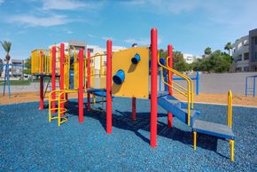 Phoenix apartment for rent - a playground with a yellow and red structure in a park at Vaseo Apartments, Phoenix, AZ High-End Apartments in North Phoenix, AZ - Vaseo - Brightly Colored Playground Structure With Jungle Gym, A Swing Set, And Monkey Bars.