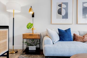 Fremont apartment for rent - A living room with a grey couch, a wooden side table with a plant, and two framed artworks on the wall.