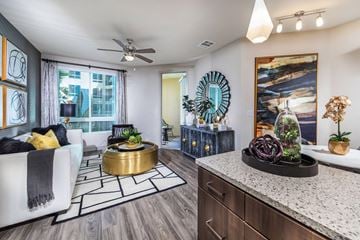 Irvine apartment for rent - A modern living room with a white sofa, a round gold coffee table, and a large painting on the wall.