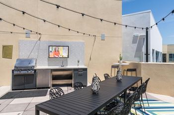 A patio with a table, chairs, and a grill.