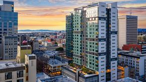 Oakland apartment for rent - A cityscape with buildings and a sunset.