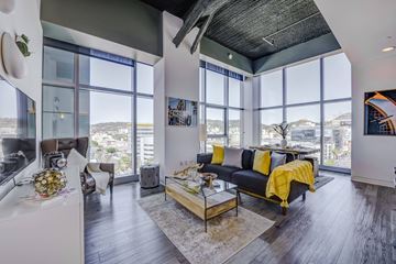 Los Angeles apartment for rent - a living room with a black leather couch and a glass coffee table with a yellow blanket on