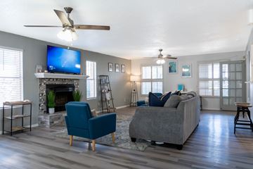 El Paso, Tx apartment for rent - A living room with a grey couch, a blue chair, a fireplace, and a television.