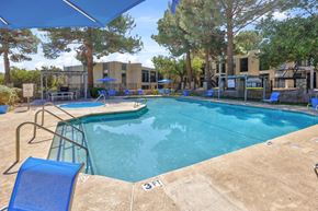 El Paso, Tx apartment for rent - A swimming pool surrounded by trees and a building in the background.