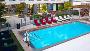Oakland apartment for rent - A pool with red chairs and a ladder.