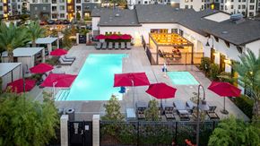 West Sacramento apartment for rent - A pool surrounded by red umbrellas and chairs.