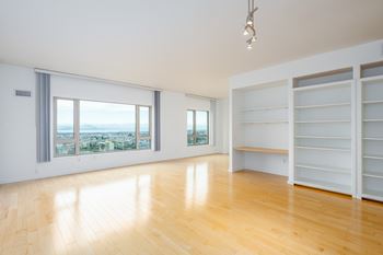 A room with wooden floors and a large window overlooking a cityscape.
