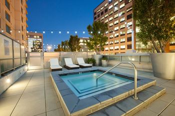 A rooftop pool with a metal railing and a few chairs.