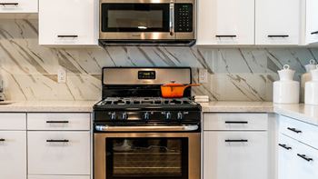 A modern kitchen with a stove, microwave, and oven.