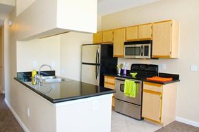 Henderson apartment for rent - A kitchen with a black counter top and stainless steel appliances at Avalon at Seven Hills Apartments, Nevada