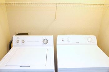 Two white washing machines in a small room.