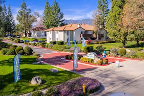Alta Loma apartment for rent - Community entrance with red brick driveway and banners at Woodbend Apartments, Alta Loma