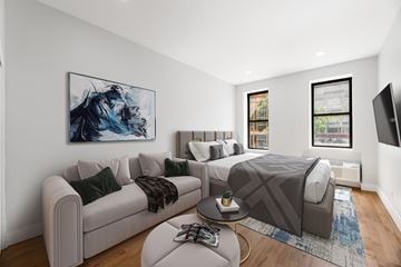 New York triplex for rent - A modern living room with a grey couch, a coffee table, and a large painting on the wall.